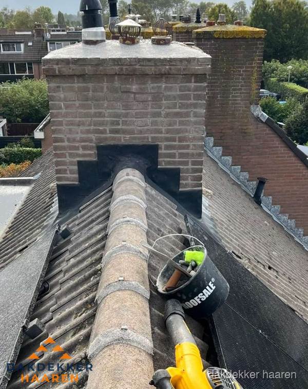 Schoorsteen met loodaansluiting en nokvorst op pannendak in Haaren