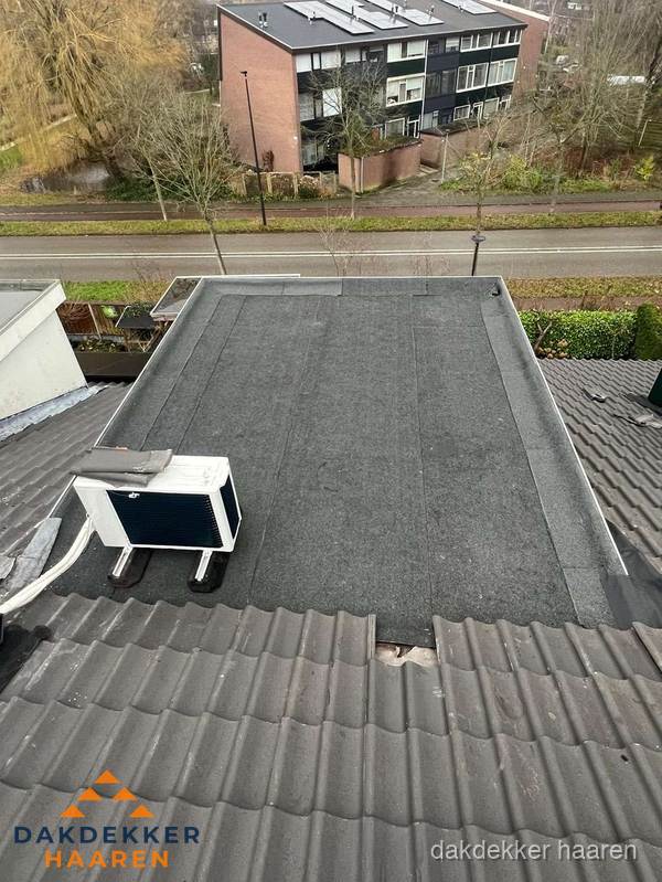 Plat dak inspectie met bitumen bedekking naast schuin pannendak in Haaren