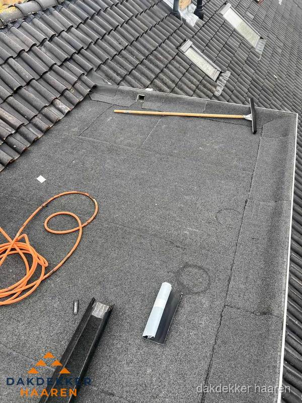 Plat dak reparatie met gereedschap en loodstroken in Haaren