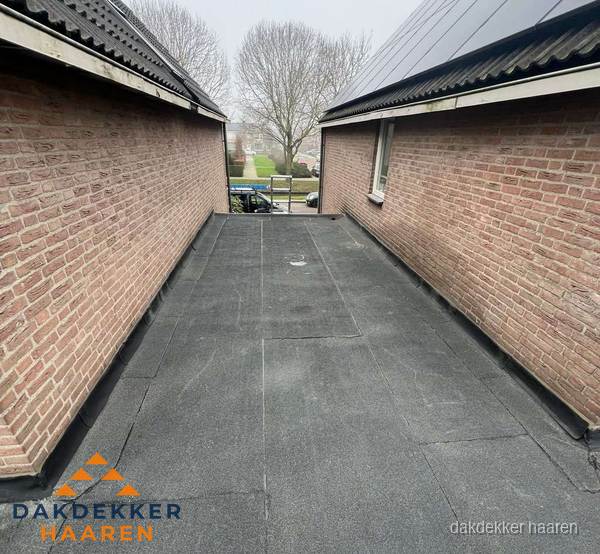 Plat dak met bitumen dakbedekking tussen bakstenen muren in Haaren Plat dak met bitumen dakbedekking tussen bakstenen muren in Haaren